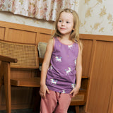 Child wearing the Maxomorra kids unicorns organic cotton vest. Purple sleeveless vest top with repeat unicorn print and light pink binding on the neck and arm holes with pink trousers. 

