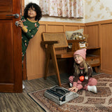 Child wearing Maxomora organic cotton green long-sleeve top. another child sitting on the floor wearing brown apple print top with pink trousers.