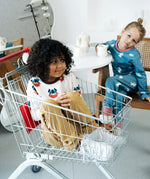 Child sitting in a trolley wearing the Maxomorra organic cotton long sleeved viking print top with mustard yellow trousers. 