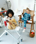 Child sitting in a trolley wearing the Maxomorra organic cotton long sleeved viking print top with mustard yellow trousers. 