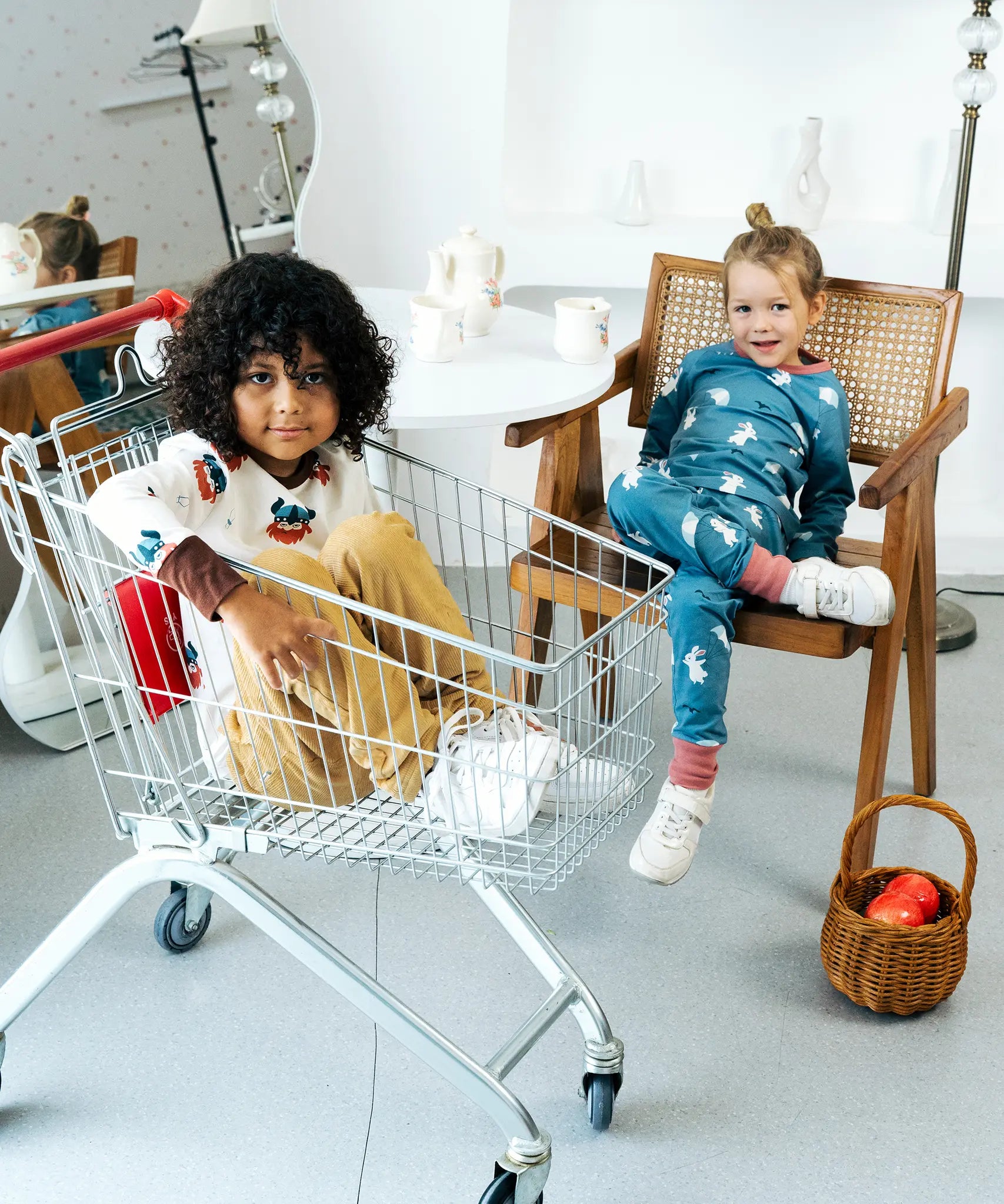 Child sitting in a trolley wearing the Maxomorra organic cotton long sleeved viking print top with mustard yellow trousers. 