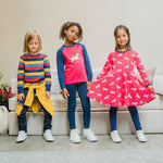 Three children wearing Maxomorra, the first is wearing stripes, the child in the middle is wearing a unicorn raglan top and the third child is wearing the Maxomorra Unicorn Long Sleeve Circle Dress.