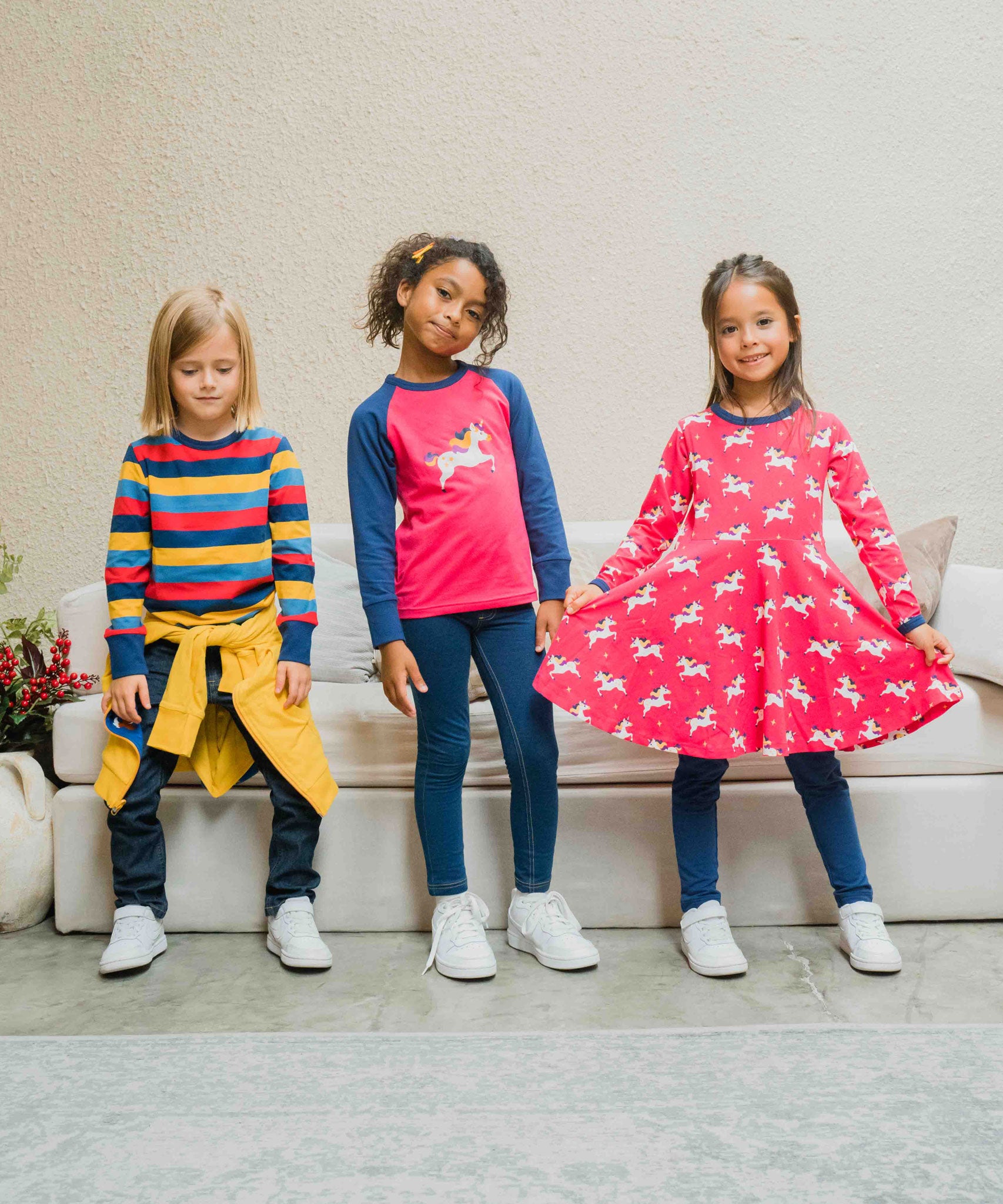 Three children wearing Maxomorra, the first is wearing stripes, the child in the middle is wearing a unicorn raglan top and the third child is wearing the Maxomorra Unicorn Long Sleeve Circle Dress.