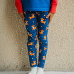 AS close up of a child wearing the Maxomorra Reindeer Leggings. The child is stood in front of a beige coloured wall. 