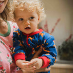 A close up of a young child wearing the Maxomorra Reindeer Long Sleeve Rompersuit.