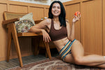 Woman wearing the Maxomorra GOTS organic cotton women's brief hipster pants in a white, yellow, blue and brown striped design with a brown organic cotton comfort bra.