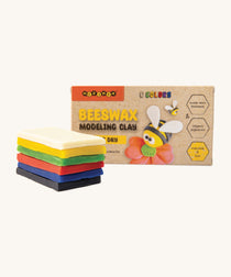 The six coloured pieces of Medenka beeswax modelling clay, in front of the packaging that features a model of a bee. 