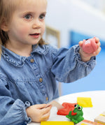 A little girl playing with some pink Medenka beeswax modelling clay. 