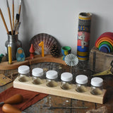 Six Mercurius glass jars placed in a wooden storage block. 