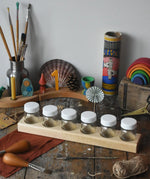 Six Mercurius glass jars placed in a wooden storage block. 