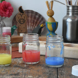 3 mercurius glass paint jar pots with lids taken off and some blue, red and yellow paint in them.