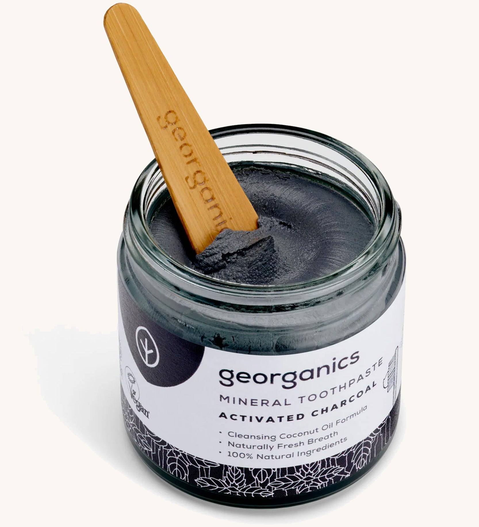 An opened jar of mineral activated charcoal toothpaste with the tongue stick dipped in