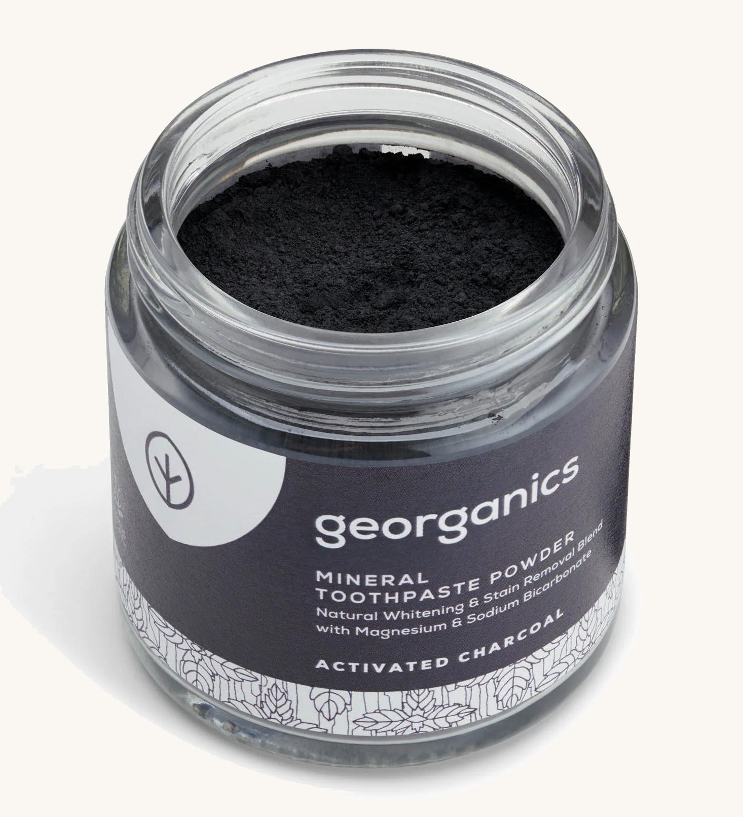  A opened jar of the charcoal Georganics toothpaste powder on a cream background