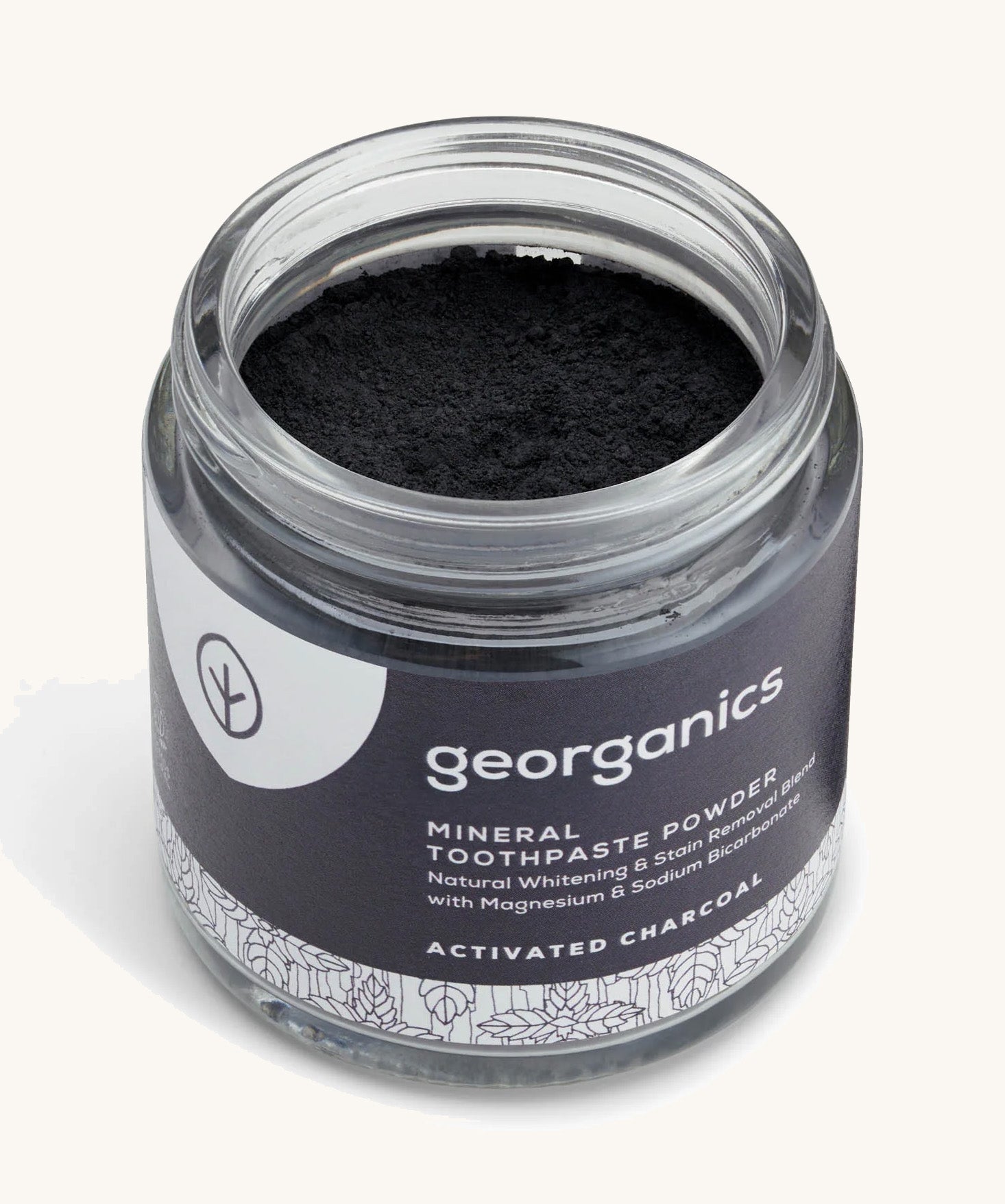  A opened jar of the charcoal Georganics toothpaste powder on a cream background