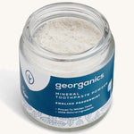  A  opened jar of the peppermint  Georganics toothpaste powder on a cream background