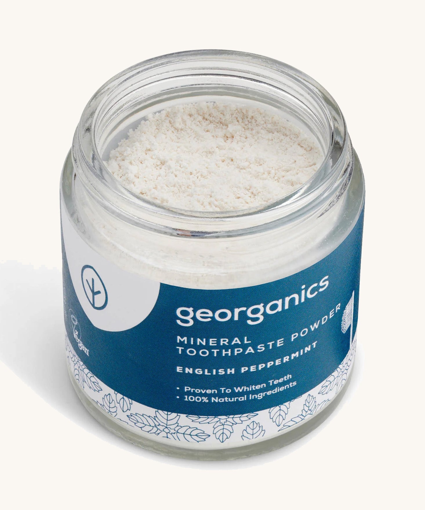  A  opened jar of the peppermint  Georganics toothpaste powder on a cream background