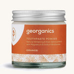  A jar of the orange Georganics toothpaste powder on a cream background
