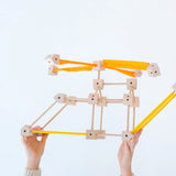 A child holding up a helicopter made from various wooden poles and blocks out of the Trigonos mini large construction set 