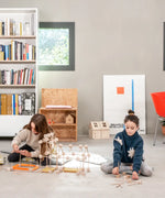 Children building a house made from various wooden poles and blocks out of the Trigonos mini large construction set 