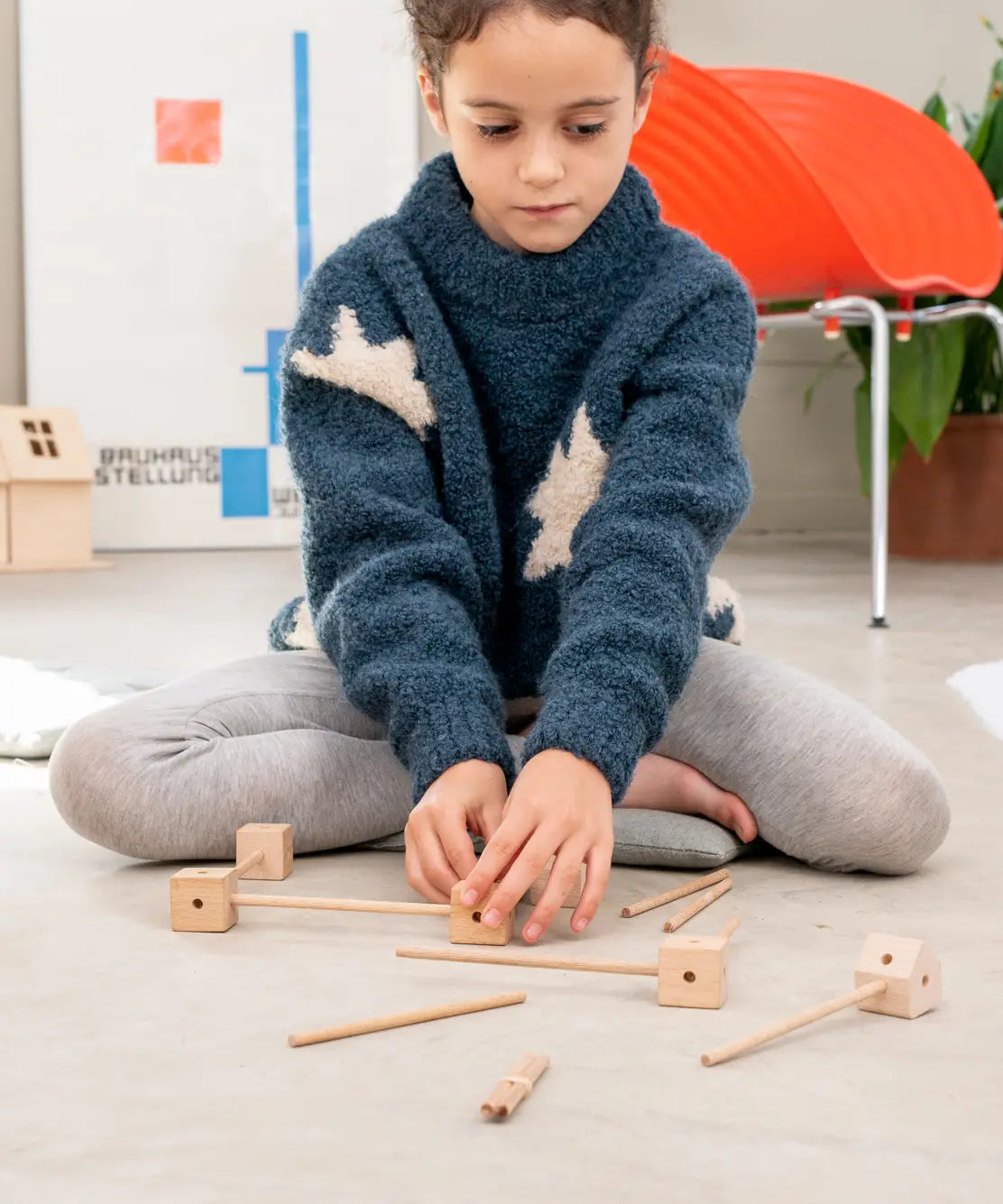 Child starting a build using various wooden poles and blocks out of the Trigonos mini large construction set 