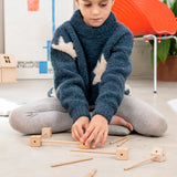 Child starting a build using various wooden poles and blocks out of the Trigonos mini large construction set 