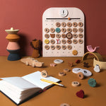 Pieces of the Moon Picnic wooden calendar scattered on a brown table in front of a red wall