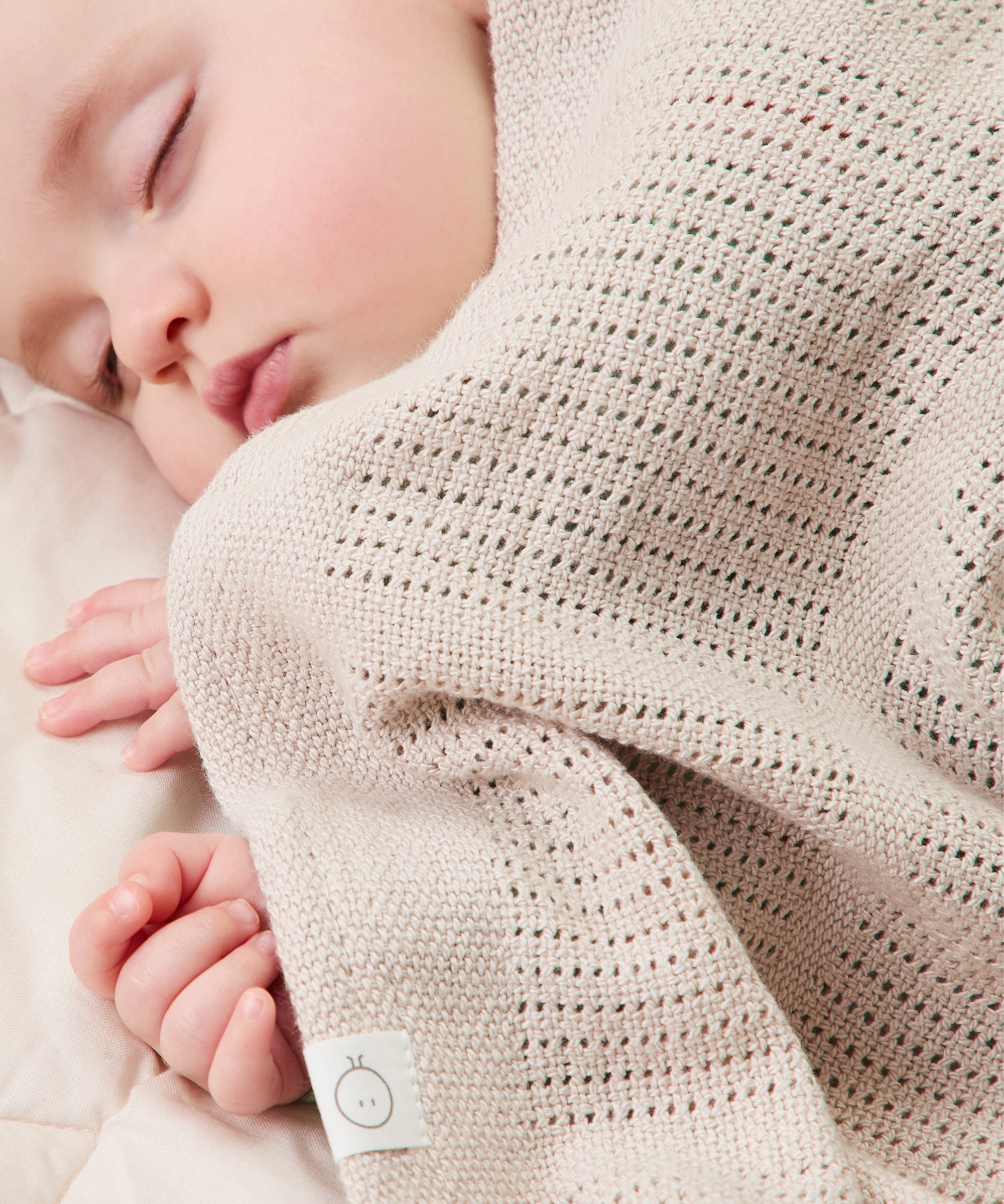 A close up of the MORI biscuit cellular blanket covering a baby showing the air hole detail for temperature control