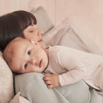 A close up of a baby resting on the mothers shoulder wearing the MORI ecru two way sleepsuit showing the ribbed detail