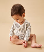 A baby sat upright, wearing a mori organic baby kimono bodysuit, in white with a grey stripy design