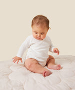 A baby wearing the Mori organic kimono baby bodysuit in white.