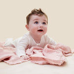 A baby crawling on the pink MORI muslin square showing the cute white prints of clouds, stars and the moon on organic cotton fabric