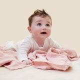 A baby crawling on the pink MORI muslin square showing the cute white prints of clouds, stars and the moon on organic cotton fabric