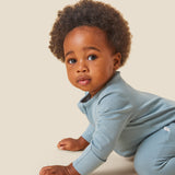 A crawling baby wearing the Mori organic zip sleepsuit in a sky blue colour