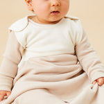 A baby sitting inside the oatmeal sriped MORI sleeping bag showing the popper fastener on the shoulder for easy fitting. 