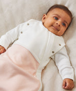A close up of the MORI blush stripe baby swaddle showing the popper detail on the arms, to tuck the arms in or let them be free.