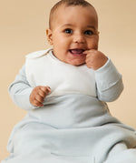 A little baby wearing the Mori organic cotton clever sleeping bag 2.5 TOG, in a blue stripe design.