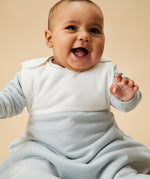 A little baby wearing the Mori organic cotton clever sleeping bag 2.5 TOG, in a blue stripe design.