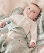 A baby lying flat on the grey MORI muslin square showing the cute dark grey prints of clouds, stars and the moon on soft organic cotton fabric