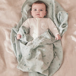 A baby wrapped up in the mint MORI muslin showing the cute print detail on organic cotton fabric