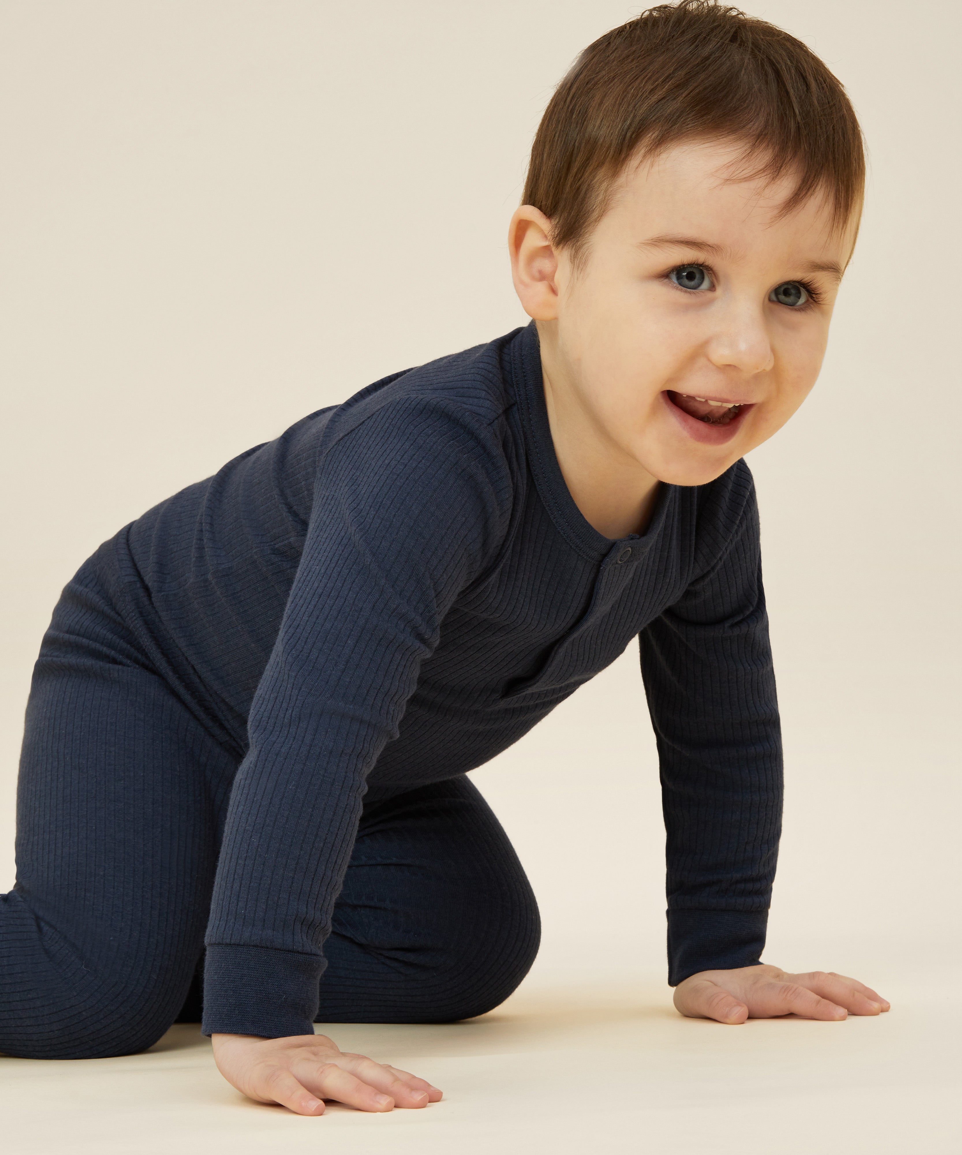 A close up of a toddler wearing the MORI ribbed style pyjama set in navy blue colour showing the popper detail on the top
