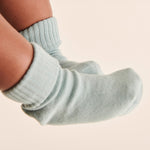 A closeup of a baby's feet, wearing light blue Mori organic cotton socks