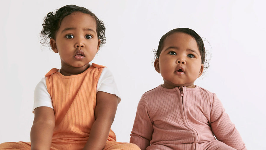 A toddler and a baby wearing organic cotton and bamboo blend Mori baby clothing.