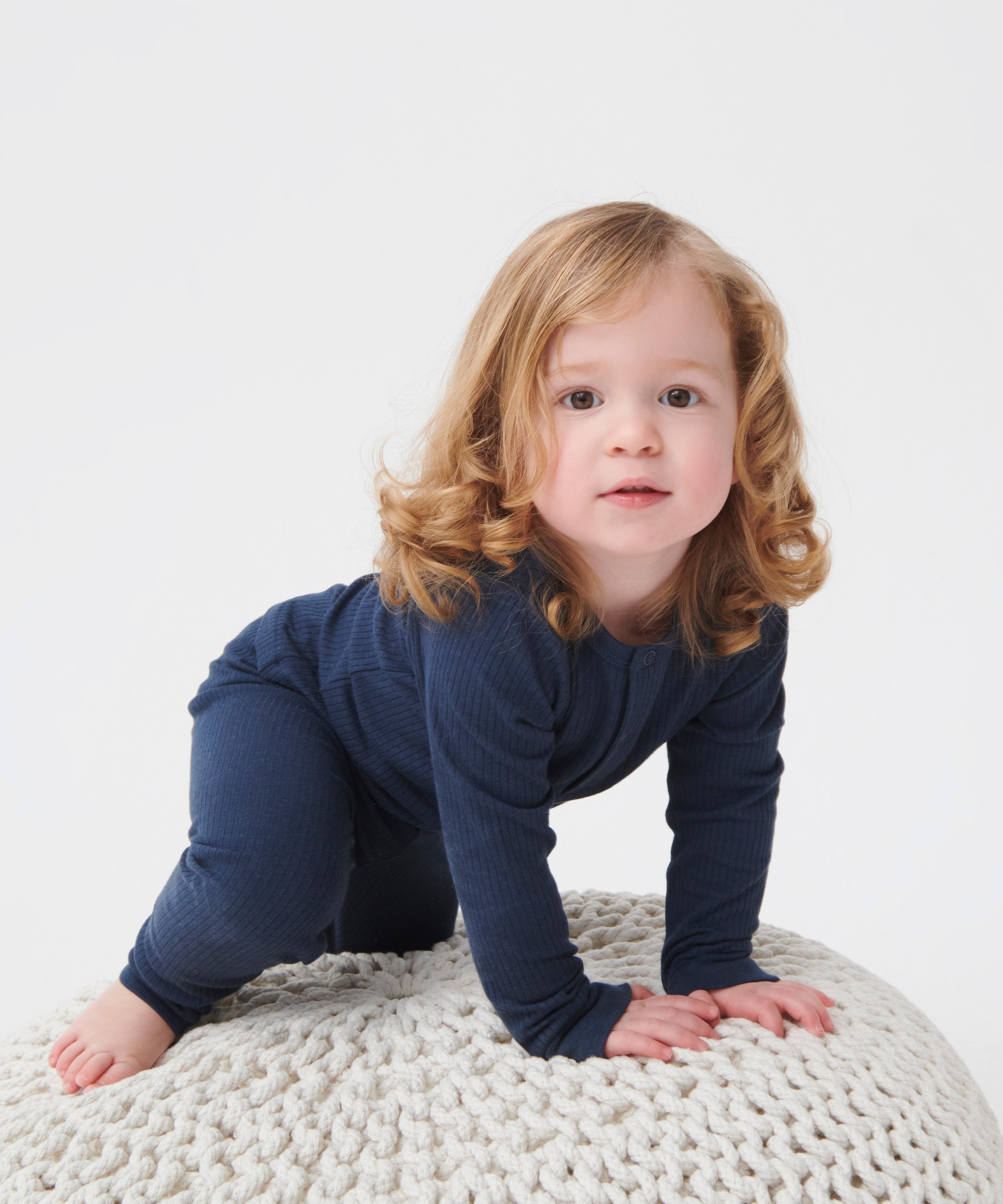A toddler crawling and wearing the MORI ribbed style pyjama set in navy colour