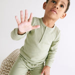 A toddler wearing the MORI ribbed style pyjama set in sage green colour showing the popper detail on the top