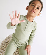 A toddler wearing the MORI ribbed style pyjama set in sage green colour showing the popper detail on the top