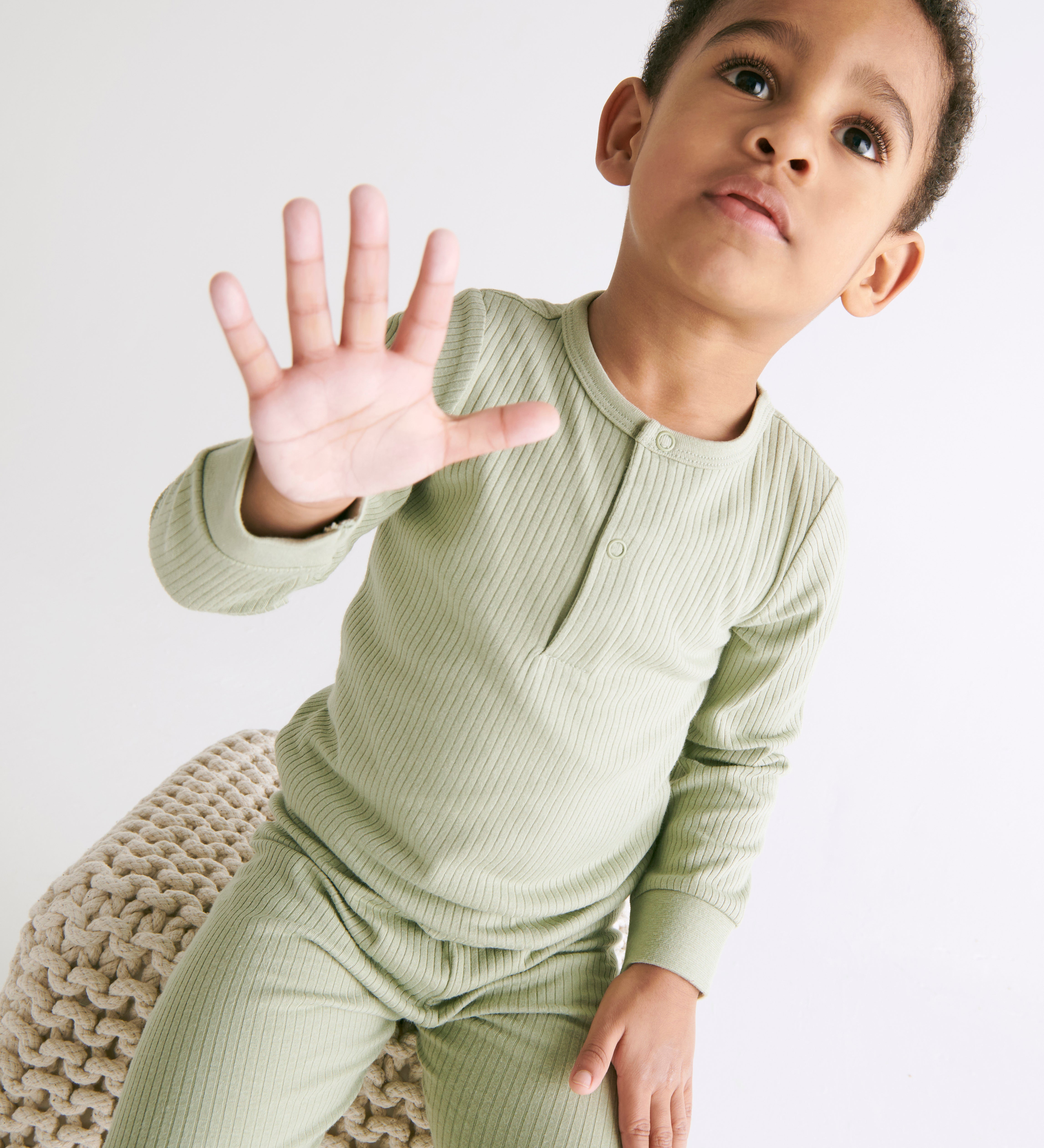 A toddler wearing the MORI ribbed style pyjama set in sage green colour showing the popper detail on the top