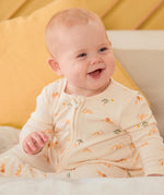 A baby sitting upright wearing the MORI lion 2 way sleep suit showing the two way zip detail and lion print detail on organic fabric