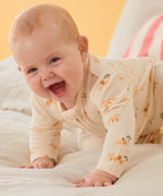 A close up of a baby wearing the MORI lion 2 way sleep suit showing the zip detail and lion print detail on organic fabric