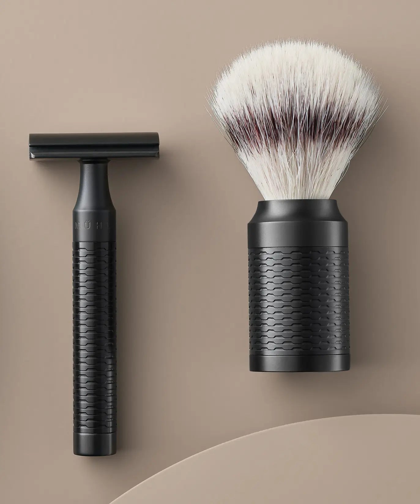 Muhle Rocca jet black stainless steel safety razor next to a maching shaving brush with silvertip synthetic fibres