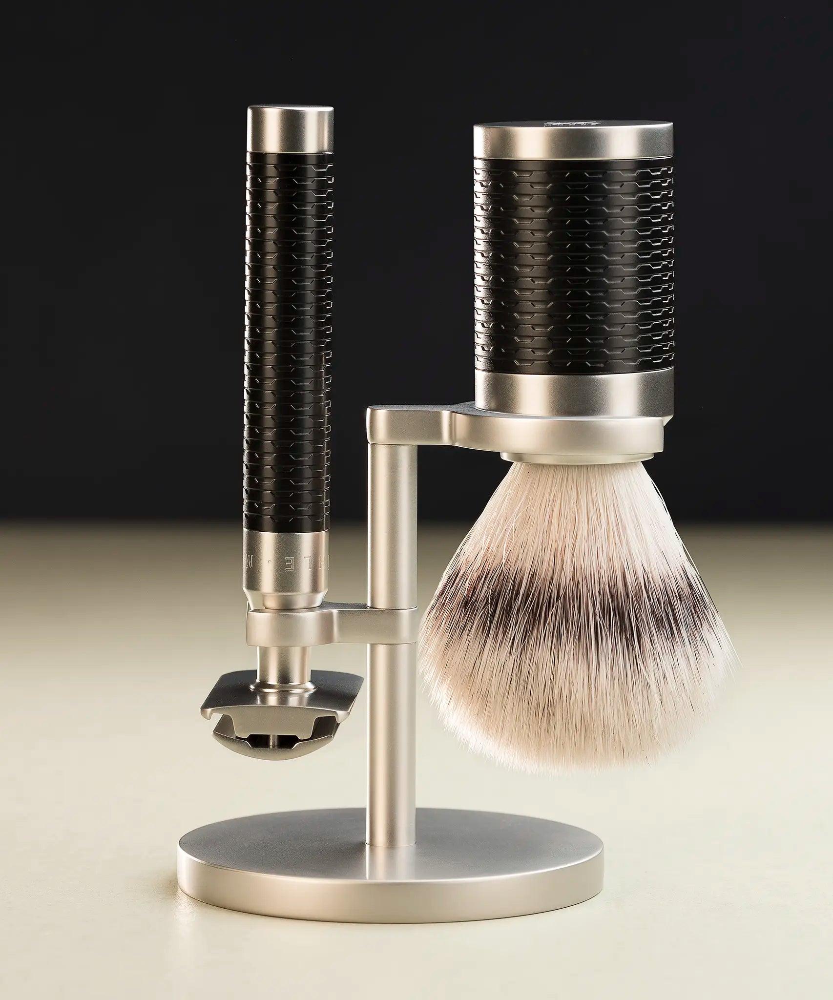 Muhle Rocca safety razor next to a maching shaving brush with silvertip synthetic fibres hanging on a stand
